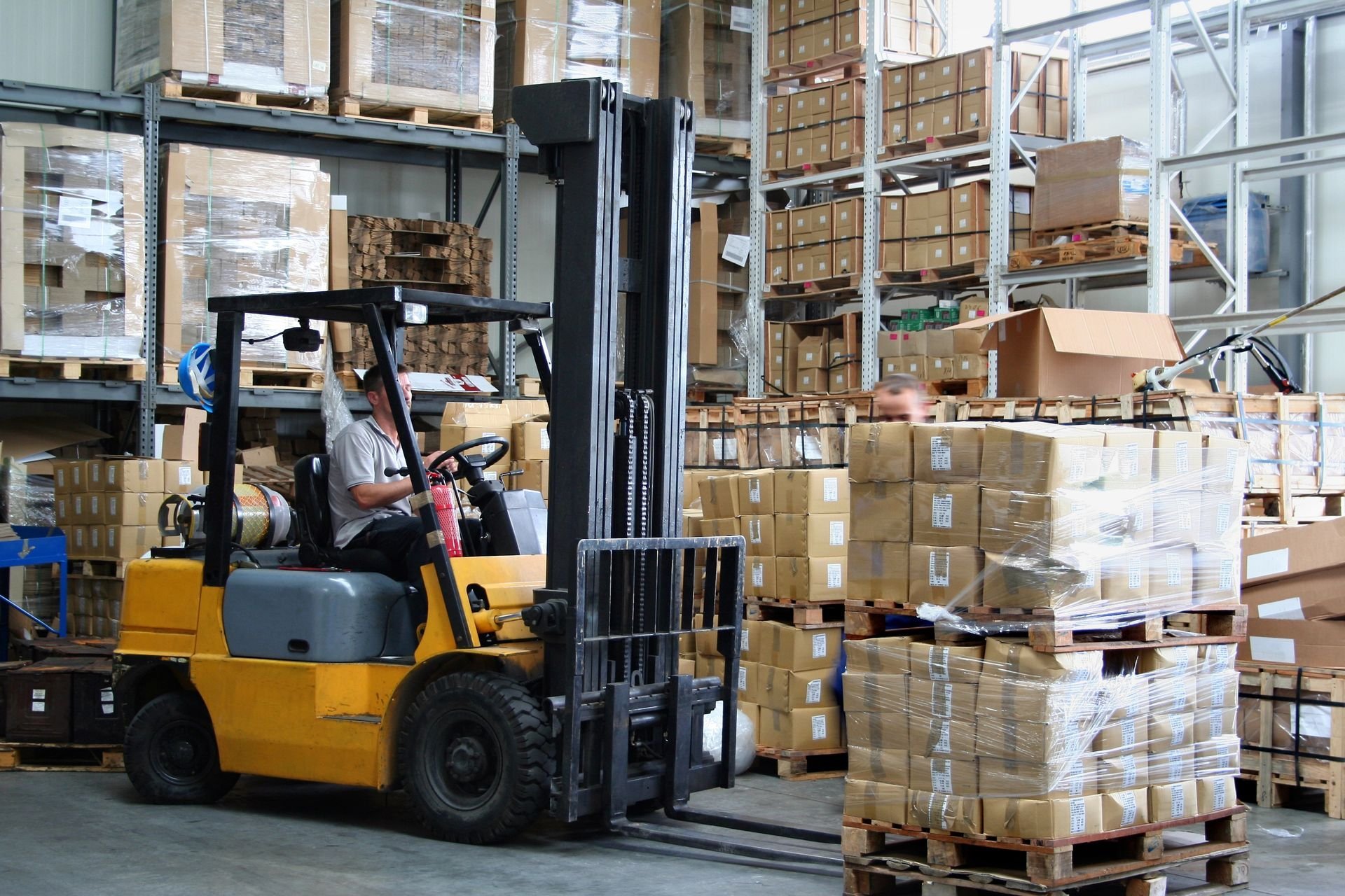 Counterbalanced forklift carrying pallets of goods in a warehouse, used for loading and material handling.
