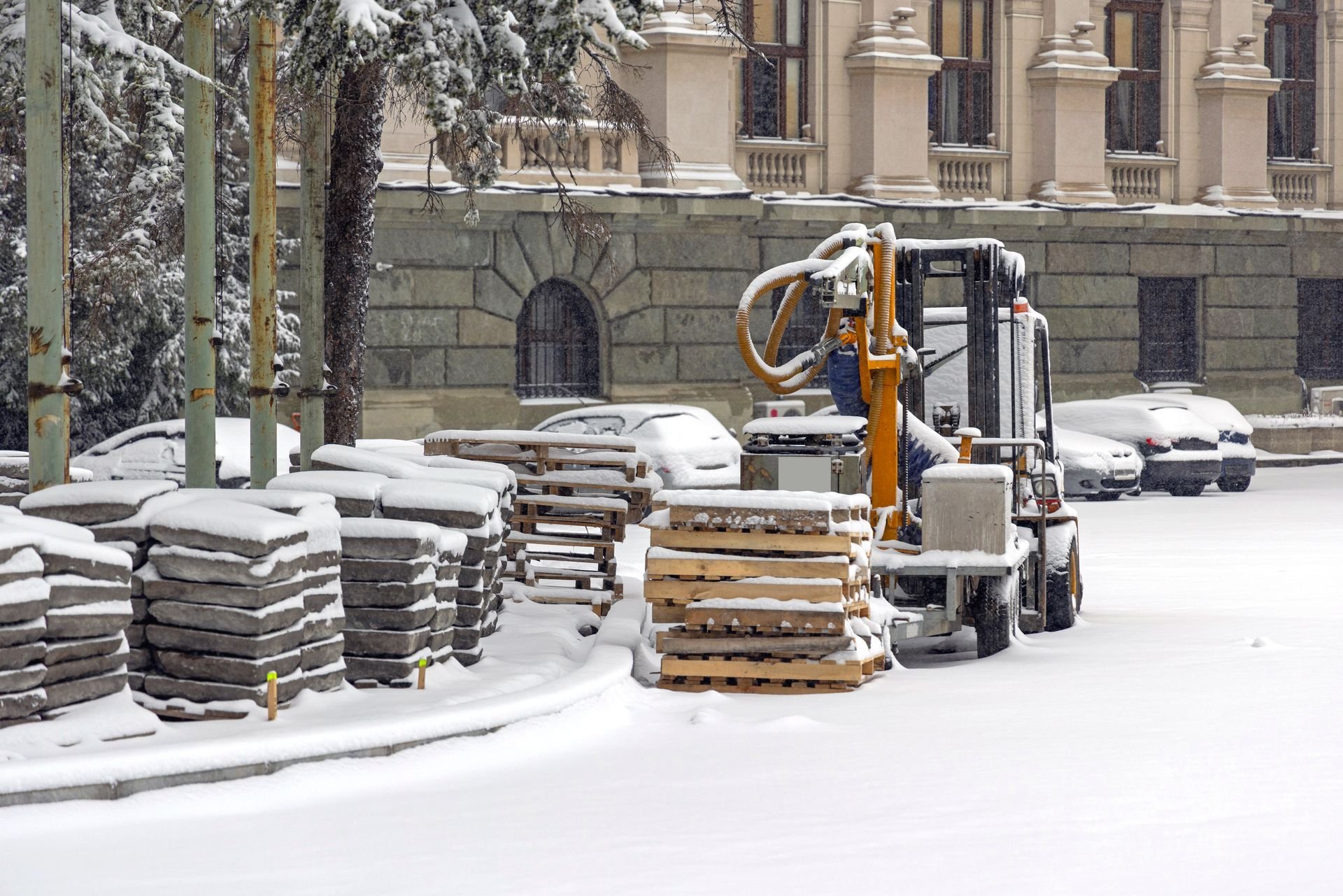 Forklift handling pallets outdoors in the snow during winter material handling operations.